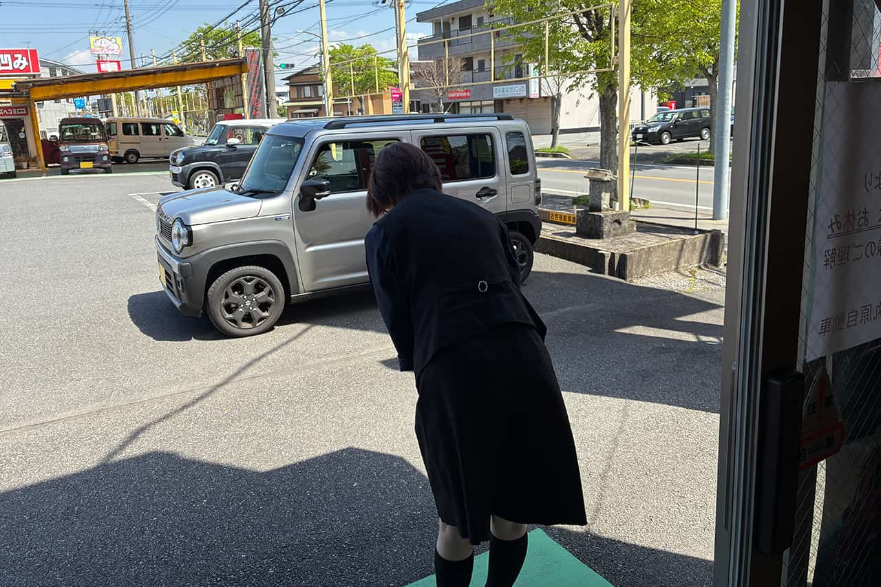 お辞儀をしてお客様をお見送りする事務員